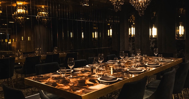 Interior, dining area, large table for ten people, ready for guests, large wall covered in mirrors