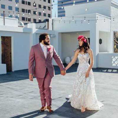 The bride and groom holding hands outside in the sunlight.