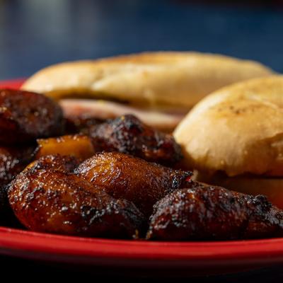 Cuban marinated pork and smoked ham sandwich served with fried plantains, close up.