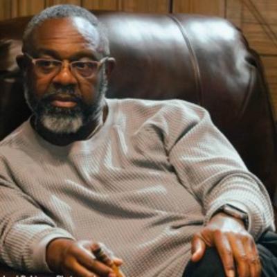 A person sitting on a leather chair and holding a cigar.