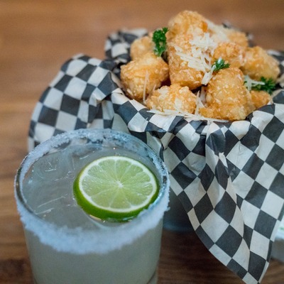 Margarita cocktail served with truffle tots topped with Parmesan cheese.