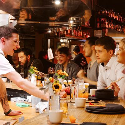 Bartender serving customers, food and drinks on the bar.