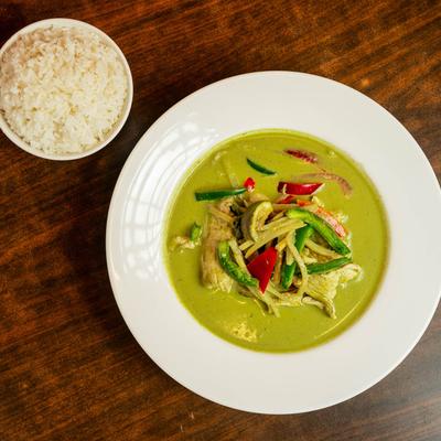 Green curry with a small bowl of white rice.