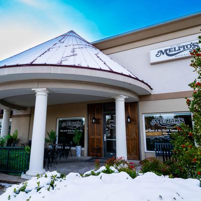 Exterior with signage featuring a snow-covered roof, columns, and outdoor seating.