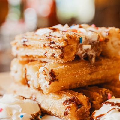 Stacked churros drizzled with chocolate sauce.