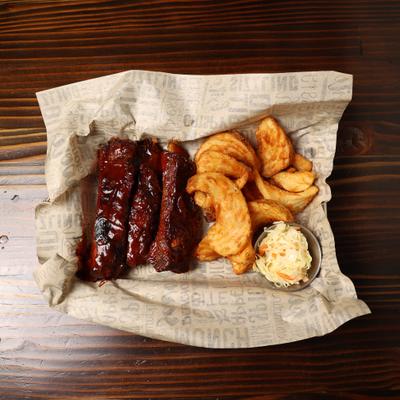 Barbecue ribs served with potato wedges and coleslaw.