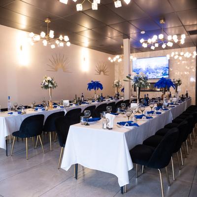 Banquet hall featuring long dining tables set with blue feather centerpieces and black chairs.