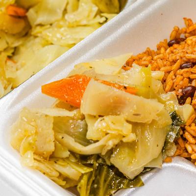Rice and peas with steamed cabbage and carrots in a take-out container.