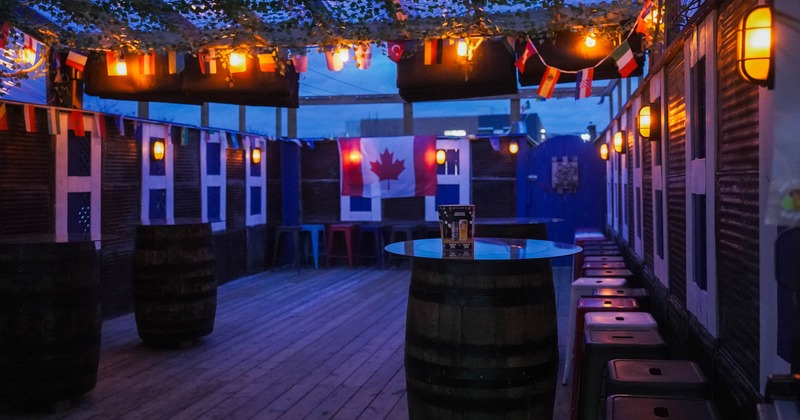 Exterior, patio space in the evening, barrel tables, bar chairs and lights