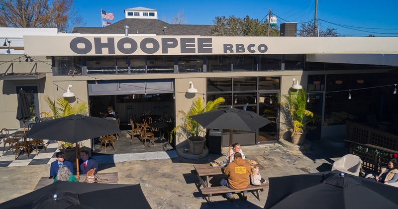 Exterior, dron shot, front of restaurant, patio, parasols, tables, chairs
