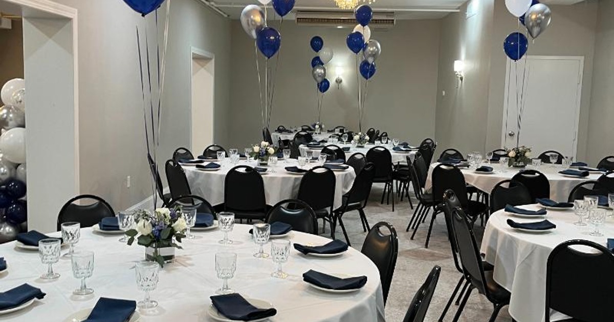 Banquet room featuring tables set with tableware, room decorated with white and blue balloons