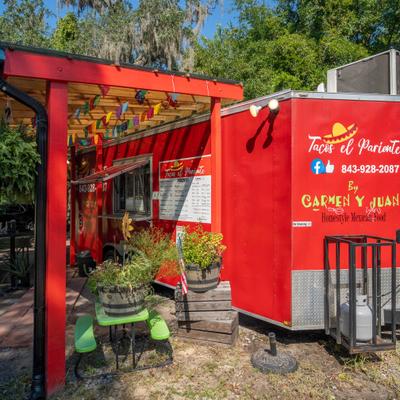 Food truck featuring bright red exterior and a covered seating area with festive decorations.