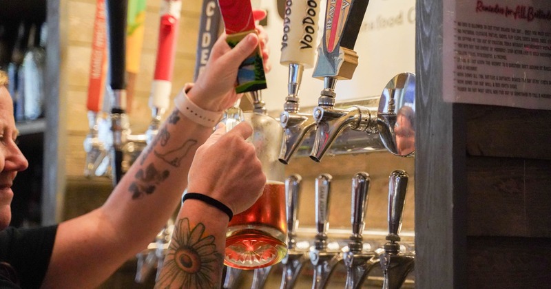 Person pouring  a glass of beer from beer taps