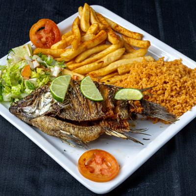 Fried fish served alongside fries, rice, salad, and lime wedges.
