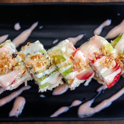 Sushi rolls topped with strawberries, kiwi, cream, and coconut flakes.