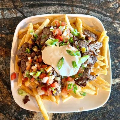 Loaded fries, with steak, cheese sauce, onions, sour cream, and pico de gallo.