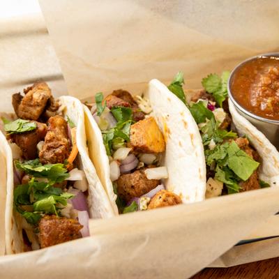 Pork belly tacos accompanied by chips and salsa.