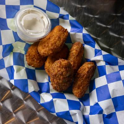 Jalapeno poppers and ranch sauce on checkered paper.