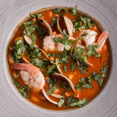 Bowl of seafood stew with shrimp, clams and fresh herbs.