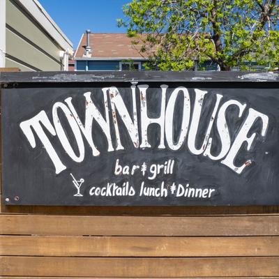 Outdoor Townhouse bar and grill sign on a wooden fence.