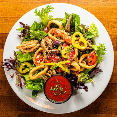 Fried calamari salad with a tomato sauce on the side.