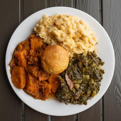 Veggie plate featuring mac and cheese, collard greens, candied yams, and a cornbread muffin.