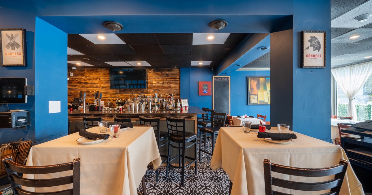 A restaurant interior with tables, a bar, and blue walls.