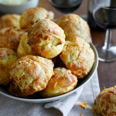 A bowl of French Cheese puffs served with red wine, close up.