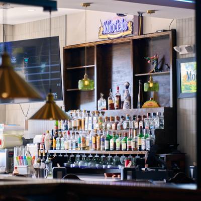 Bar interior with a wooden shelving unit holding numerous bottles of alcohol.