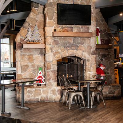 Interior, decorated dining area with big TV hanging on the wall above fireplace