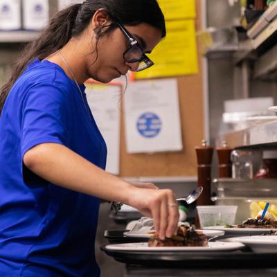 Person in a blue shirt prepares food in a kitchen.