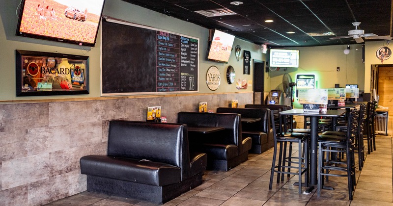 Interior of a restaurant with booths, high chairs, TVs, and a chalkboard