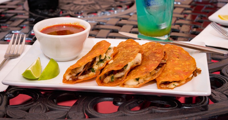 Crispy folded tortillas served with red dipping sauce