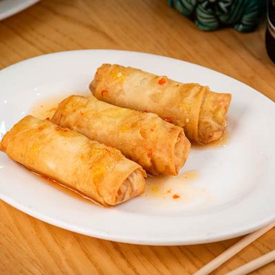 Three chicken spring rolls on a white plate.