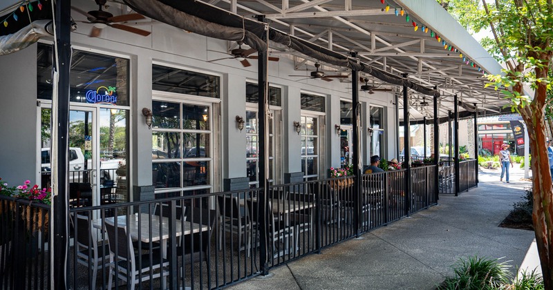 Outdoor restaurant seating area with tables, chairs and ceiling fans