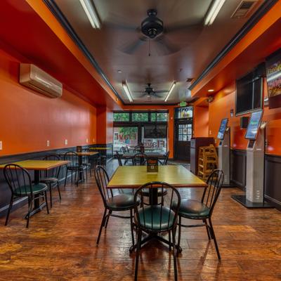 Interior featuring orange walls digital menus and dark wood tables.