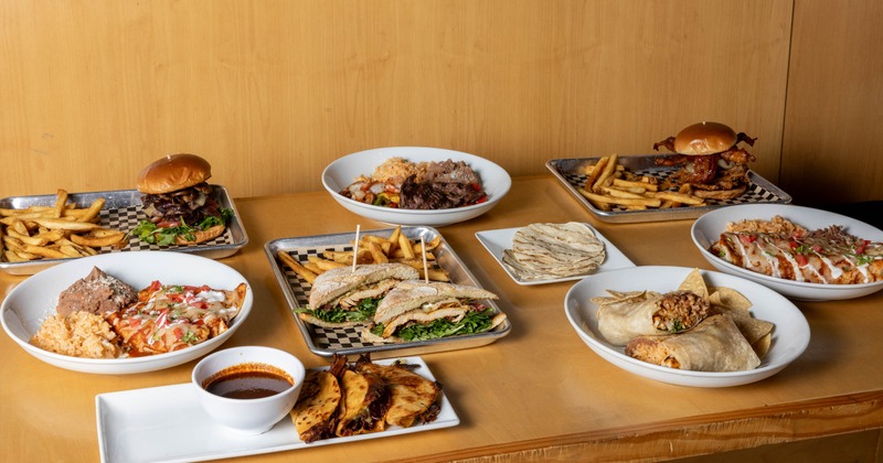 A spread of assorted  dishes and burgers with fries on a table