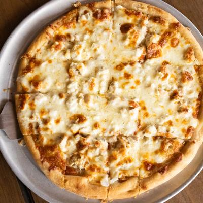 Whole pizza topped with chicken and melted cheese.