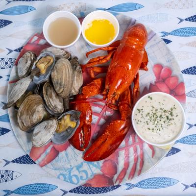 Lobster and steamed clams served with chowder and drawn butter on a plate.