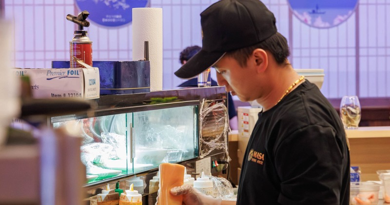 Chef preparing food behind a sushi bar