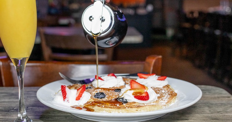 Pancakes, with whipped cream, strawberries, and maple syrup