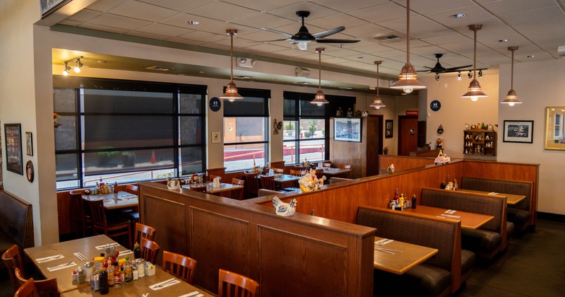 Interior of a restaurant with wooden booths, copper pendant lights, and framed pictures on the walls