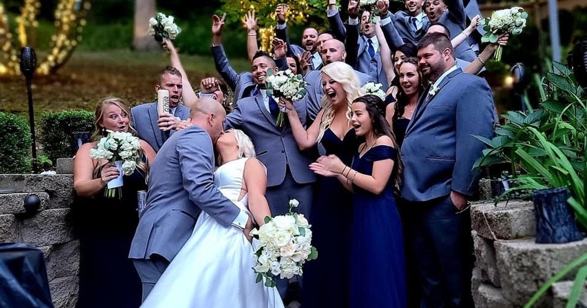 Newlyweds kissing in front of bridesmaids and groomsmen