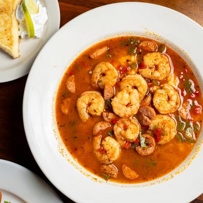 A bowl of spicy shrimp gumbo with vegetables and sausage.