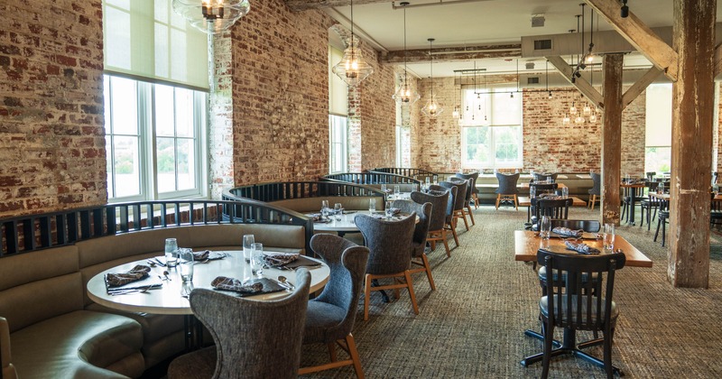 Interior, exposed brick walls, large windows, and a mix of curved booths and chairs