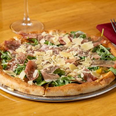 Prosciutto and arugula pizza topped with shaved Parmesan.