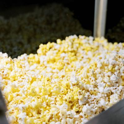 Freshly popped yellow and white popcorn piled inside a metal warming bin.