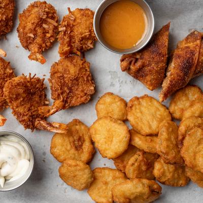 Sampler platter featuring crispy shrimp, chicken nuggets, and tasty dipping sauces.