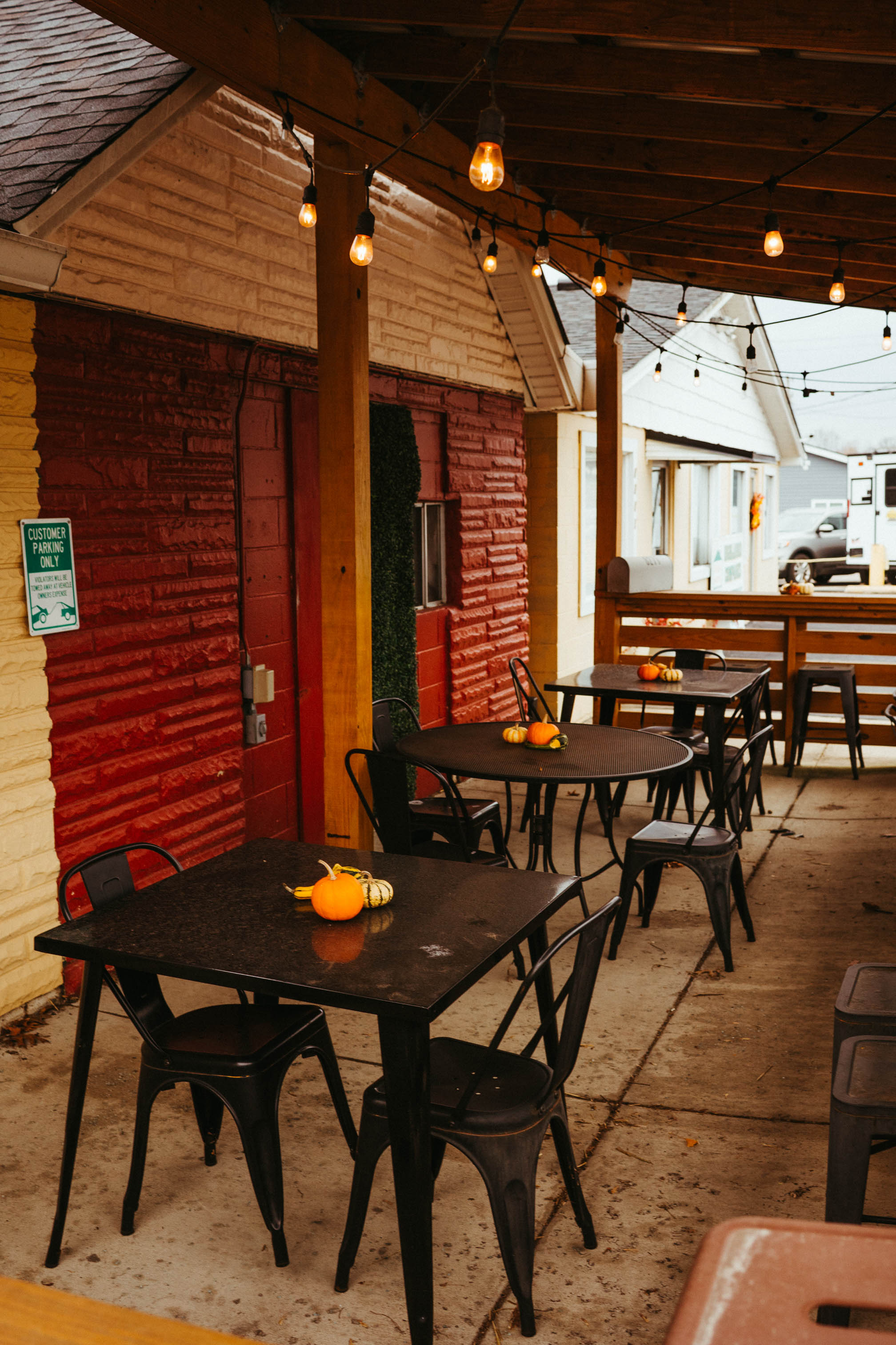 Covered patio with black metal tables and string lights