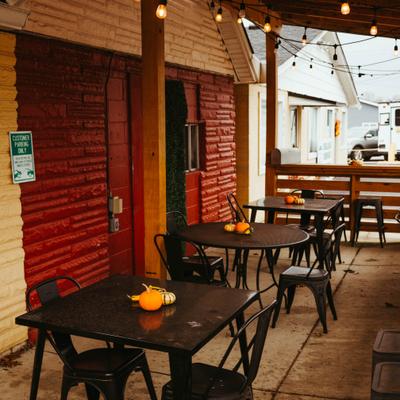 Covered patio with black metal tables and string lights.